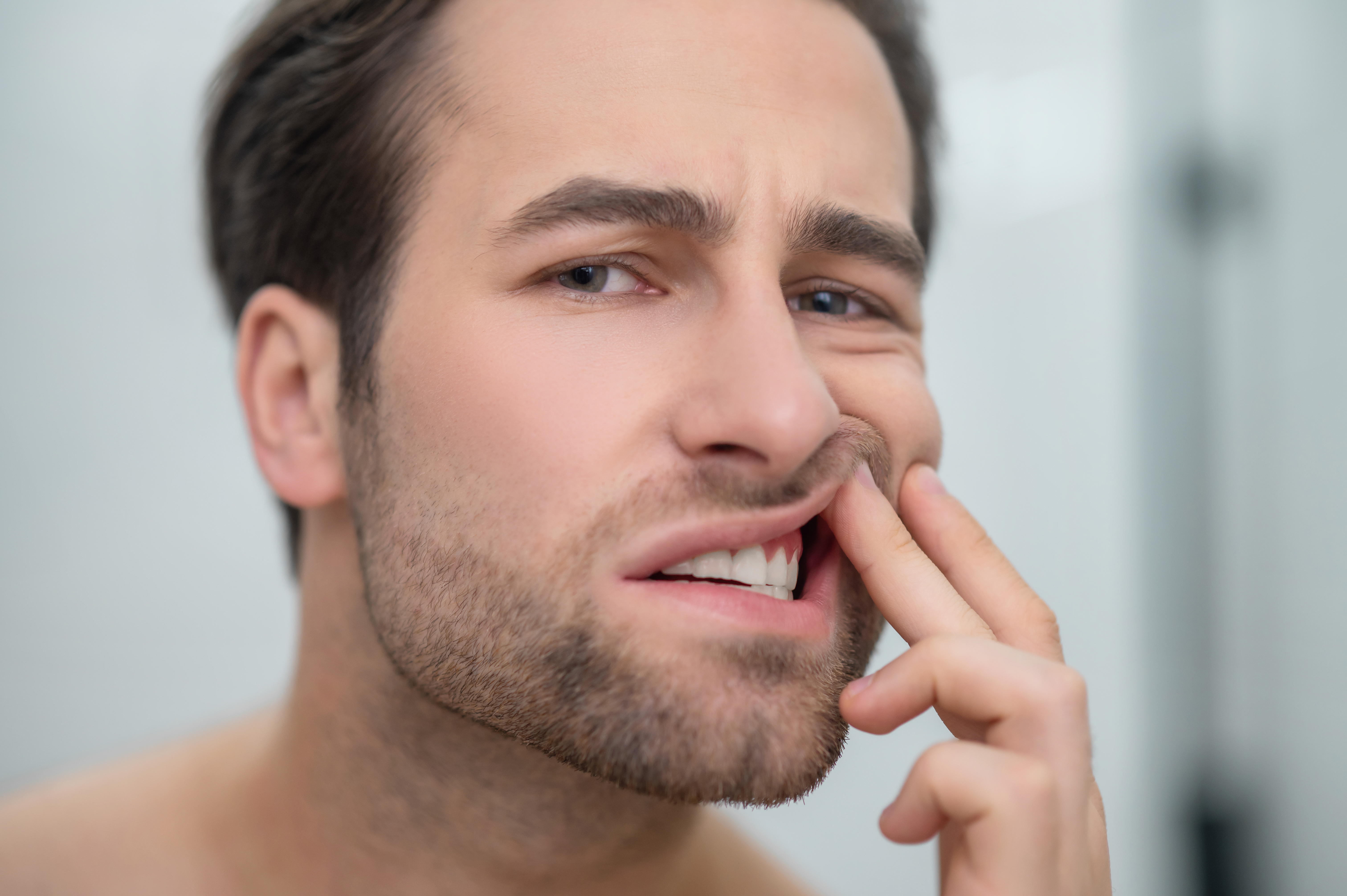 Man holding his cheek with tooth pain when biting down