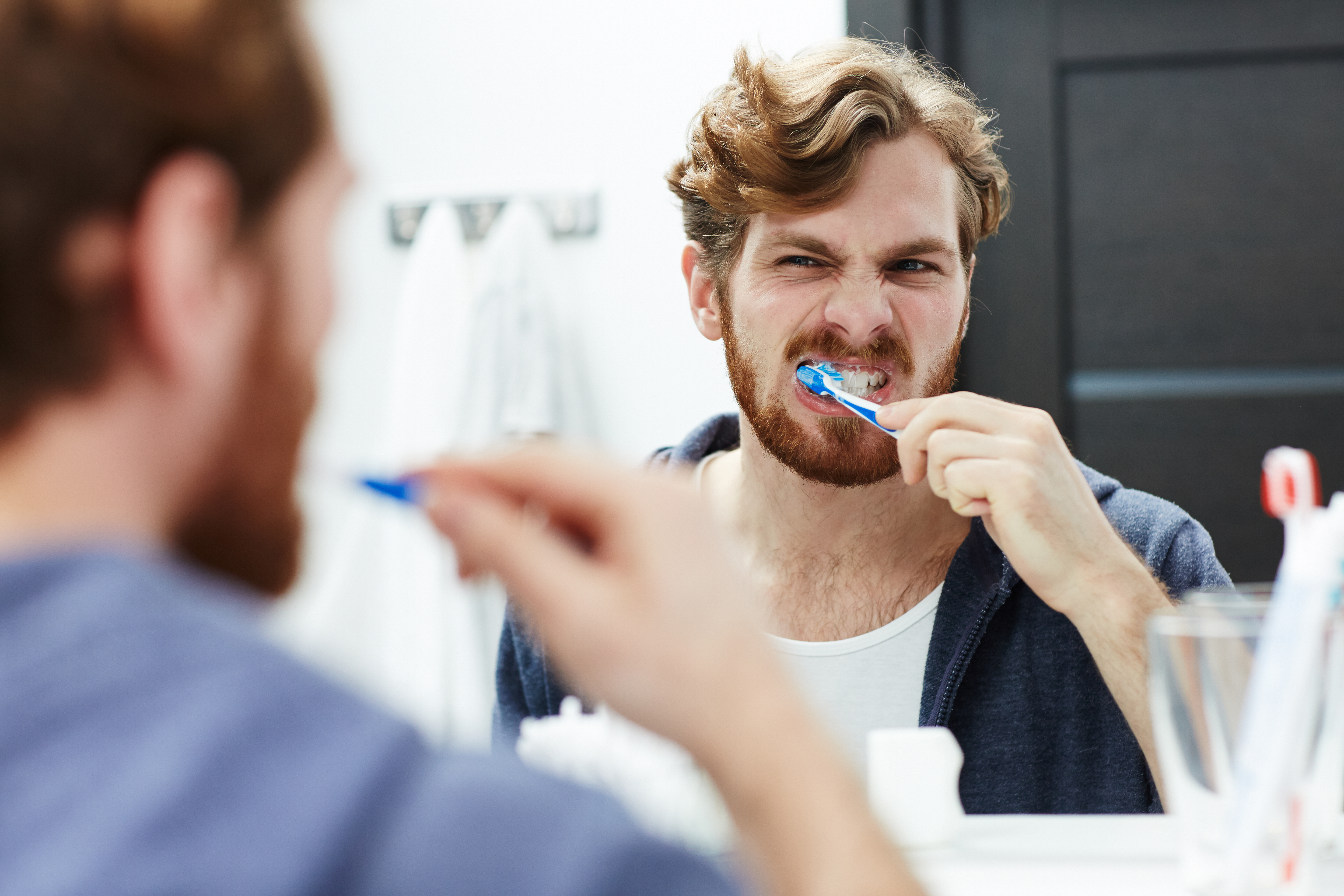 Person brushing teeth and checking for bleeding gums and a metallic taste